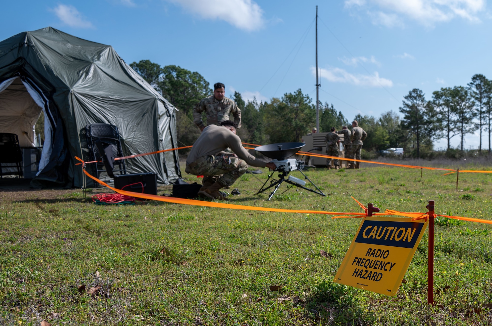 People working on a satellite dish and tactical communications tools during a training exercise.