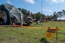 People working on a satellite dish and tactical communications tools during a training exercise.