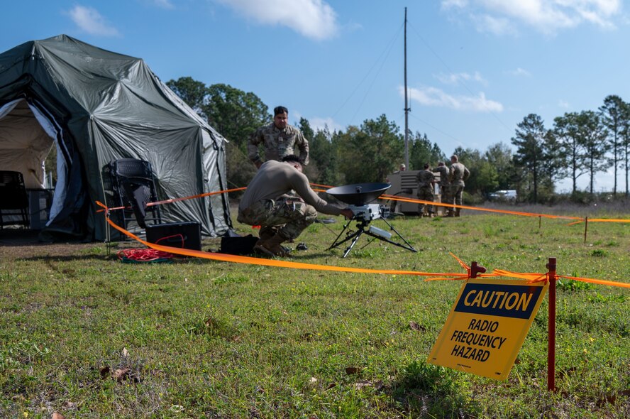 People working on a satellite dish and tactical communications tools during a training exercise.
