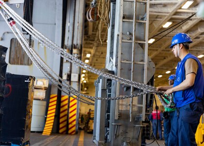 Boatswain’s Mate 3rd Class Chris Bustos, assigned to deck department aboard the world’s largest aircraft carrier, USS Gerald R. Ford (CVN 78), holds a line in the hangar bay during a replenishment-at-sea (RAS), April 4, 2025.