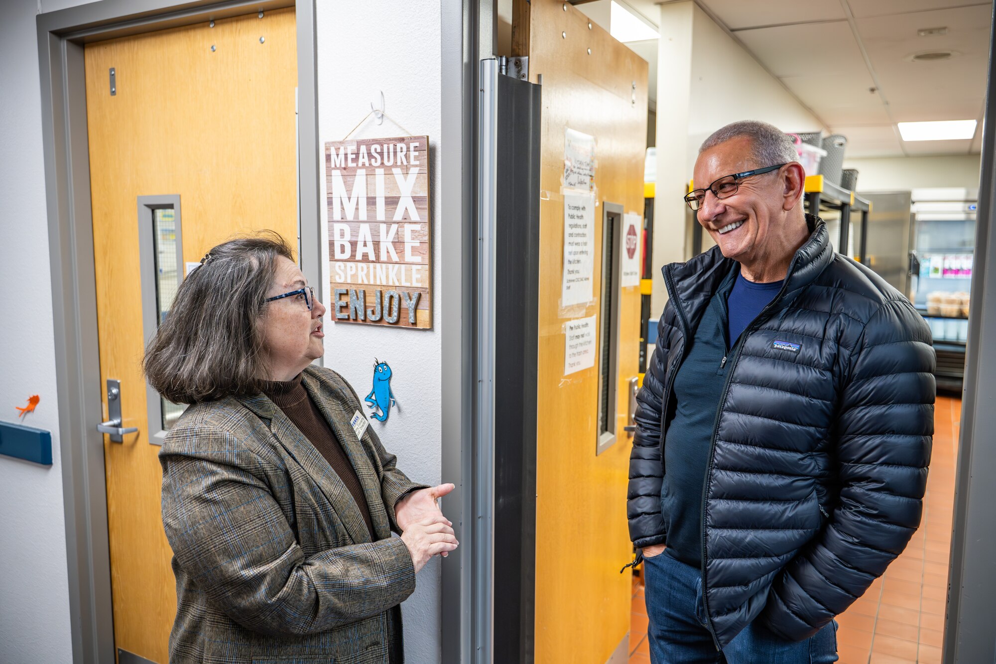 Celebrity chef Robert Irvine discusses the menu offered to the children of the Child Development Center with Tamara Finnerty, 50th Force Support Squadron CDC assistant director, at Schriever Space Force Base, Colorado, April 3, 2025. During his visit to Schriever SFB, Chef Irvine and the Robert Irvine Foundation toured the CDC kitchen and the base dining facility, The Dish, to engage with Guardians, Airmen, and staff. (U.S. Space Force photo by Dalton Prejeant)