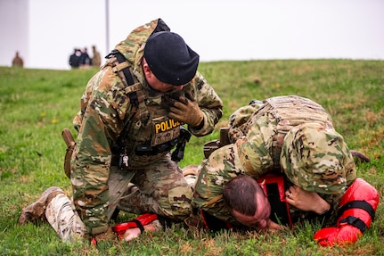 U.S. Air National Guard Master Sgt. Bryan Wright from the 134th Security Forces Squadron radios dispatch while Tech. Sgt. Ryan Sharp restrains a suspect during a perimeter breach exercise on McGhee Tyson Air National Guard Base, Tennessee, April 6, 2025.