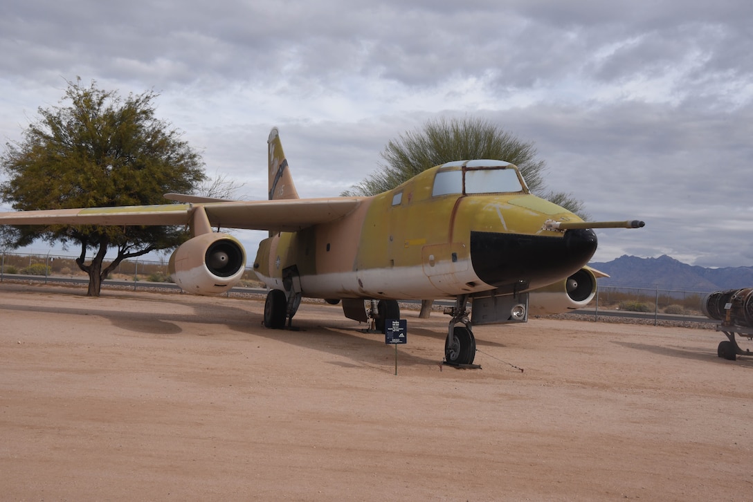 An airplane is on display in a dirt field with trees in the background.