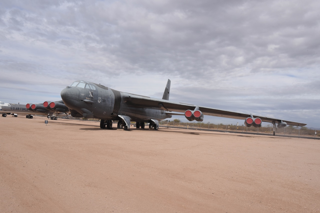 An airplane is on display in a dirt field with another aircraft to the left.