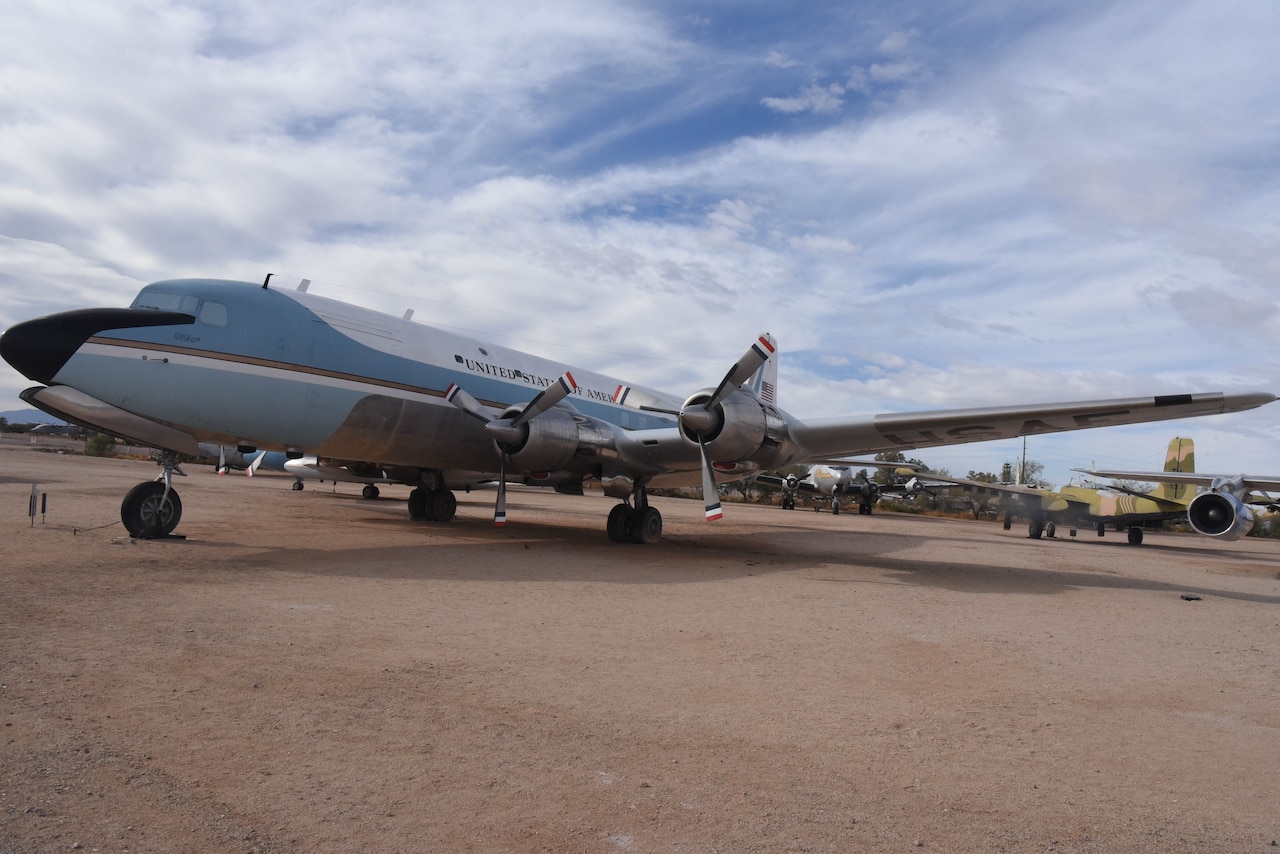 An airplane is on display in a dirt field with aircraft behind it.
