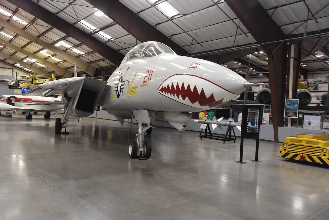 An airplane is on display in a large building with other aircraft behind it.