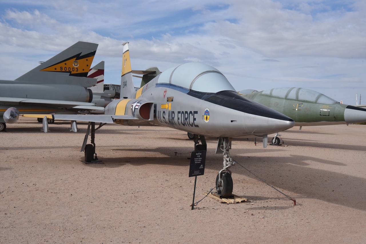 An airplane is on display in a dirt field with aircraft around it.