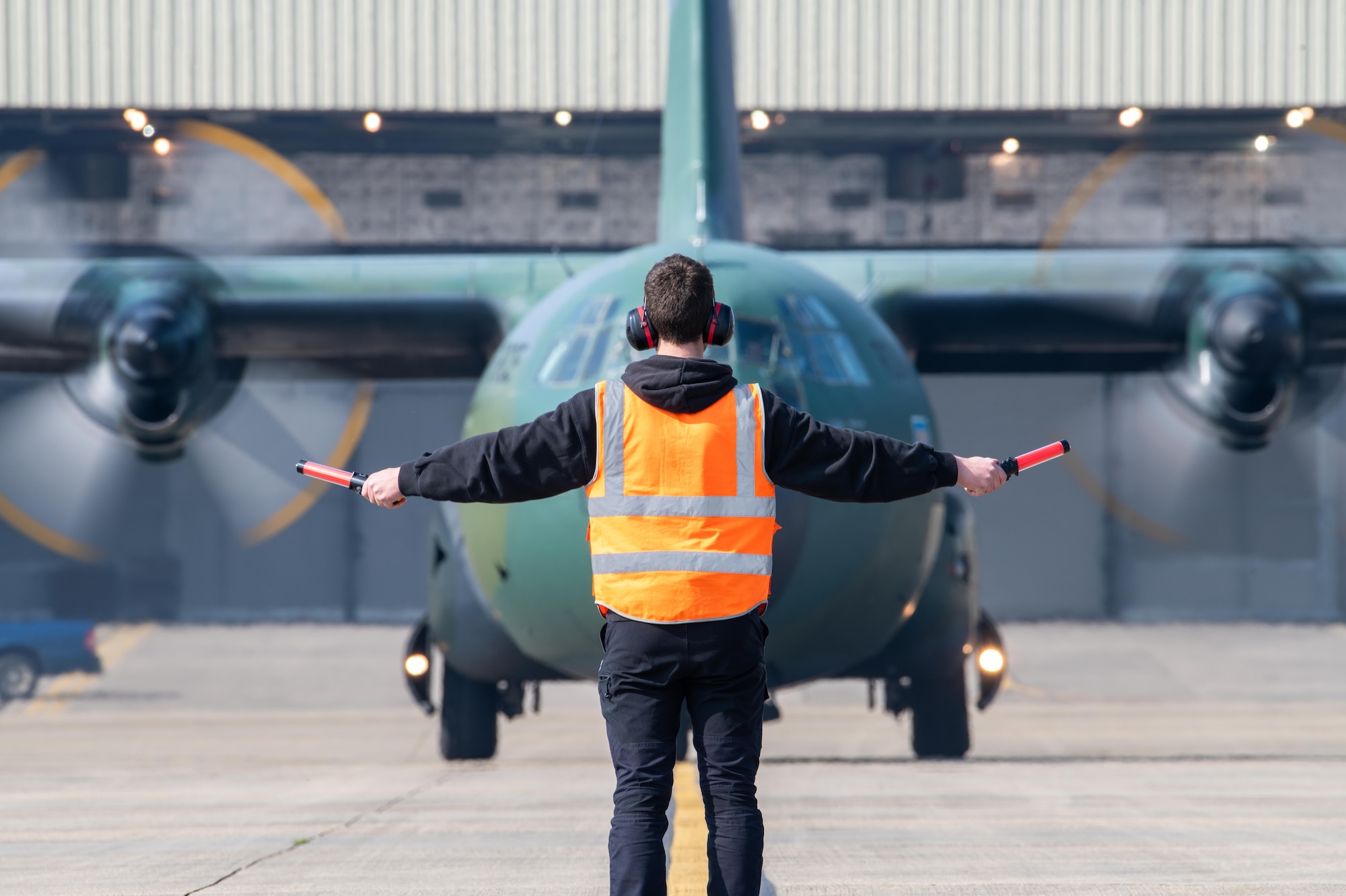 A crew chief assigned to the 501st Combat Support Wing (CSW), guides in a taxiing Romanian Air Force (RoAF) C-130 Hercules