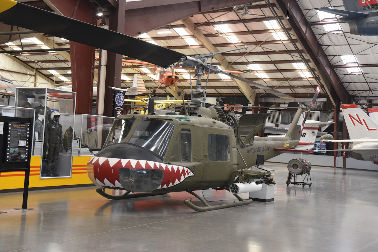 A helicopter and other aviation equipment are on display in a large building.
