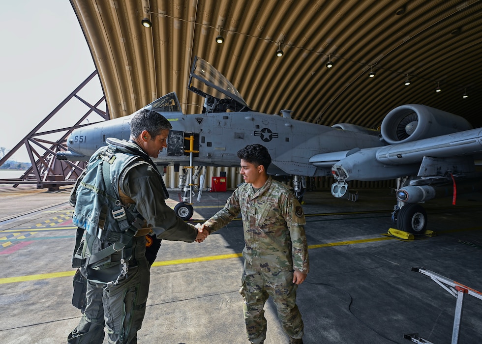 A pilot and a crew chief are shaking hands in front of an A-10 Thunderbolt II.