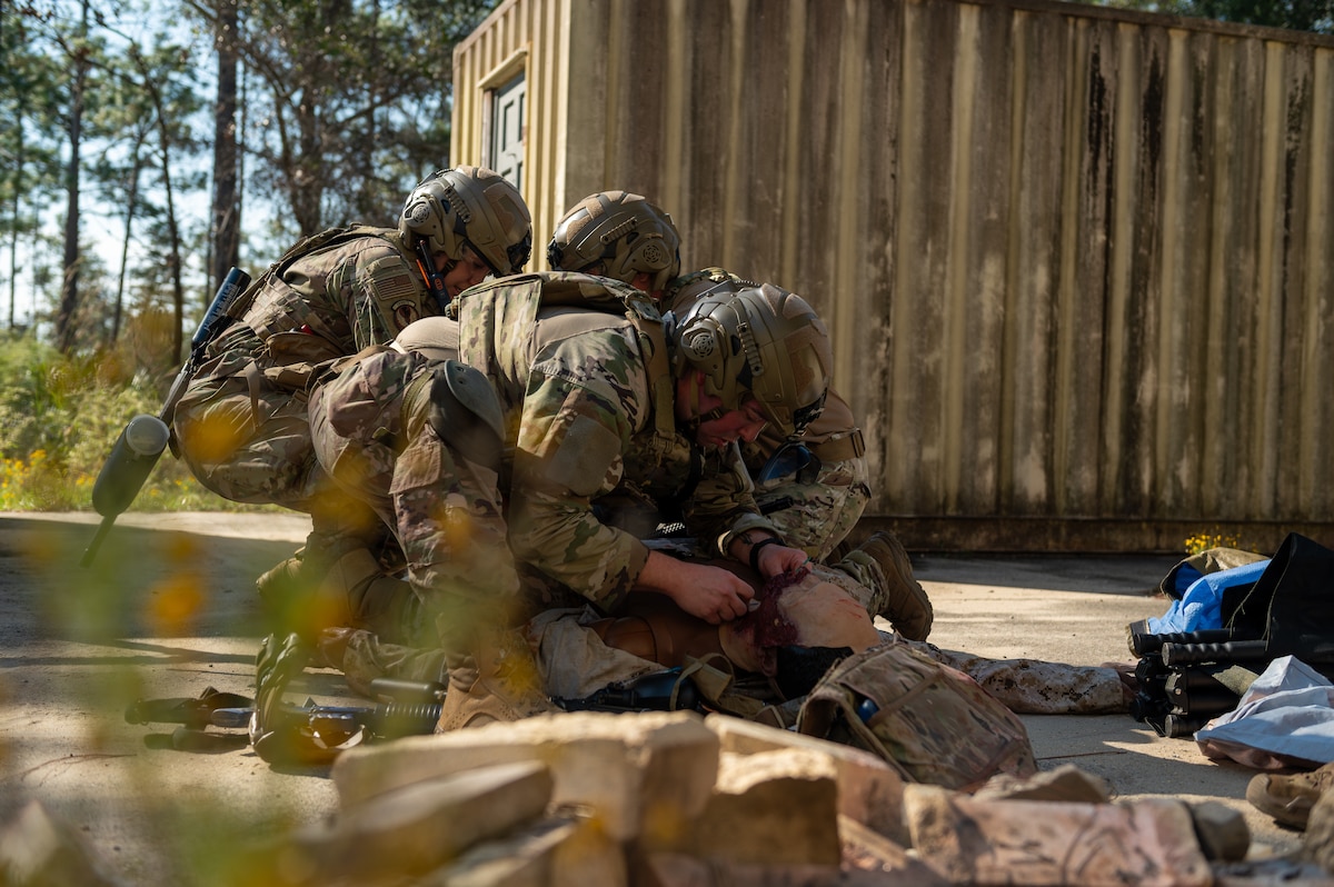 Medical Airmen perform a surgical airway procedure on a simulated burn victim.