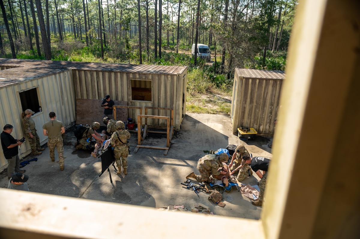 Wide shot of medical Airmen performing tactical field care on simulated casualties.