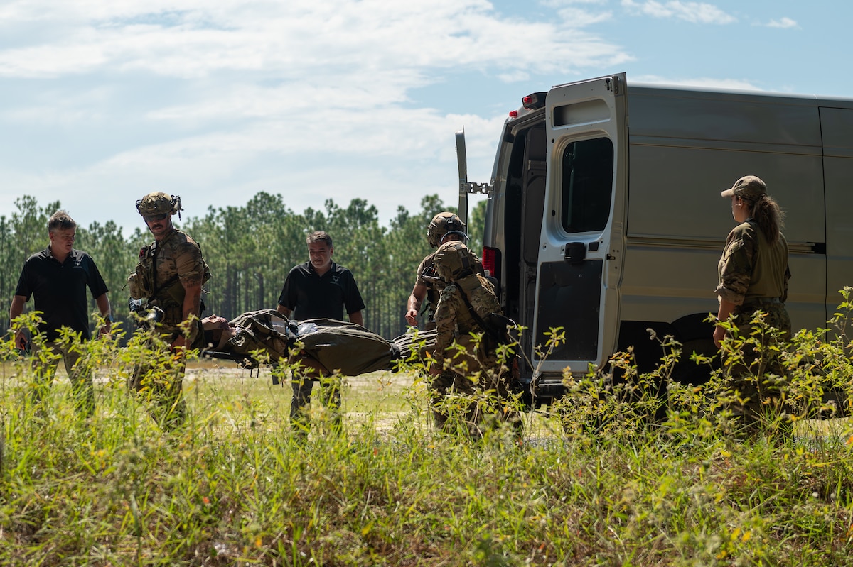 Medical Airmen transfer a simulated casualty patient on a stretcher onto the back of a van.