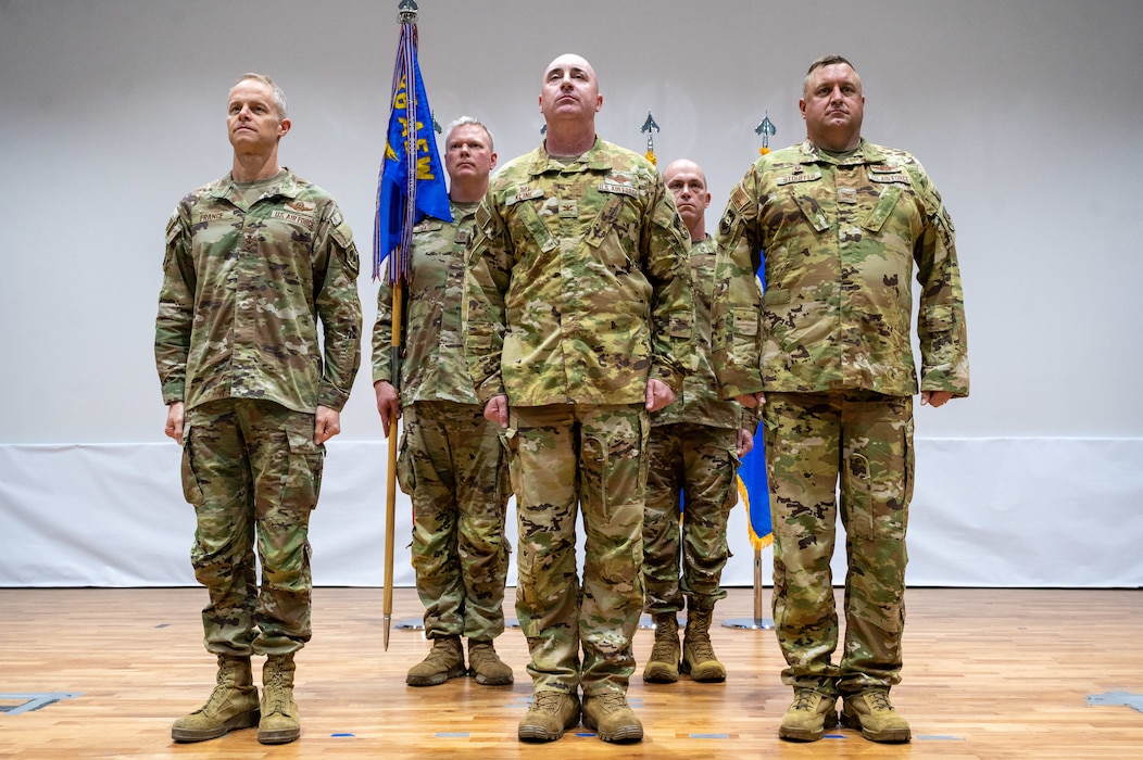 Lt. Gen. France stands at attention left of frame while Col. Kline and Col. Stouffer, outgoing and incoming commanders respectively, stand at attention to his right. In the background, from left to right, is Chief Pease and Chief Ski, the ougoing and incoming command chiefs respectively