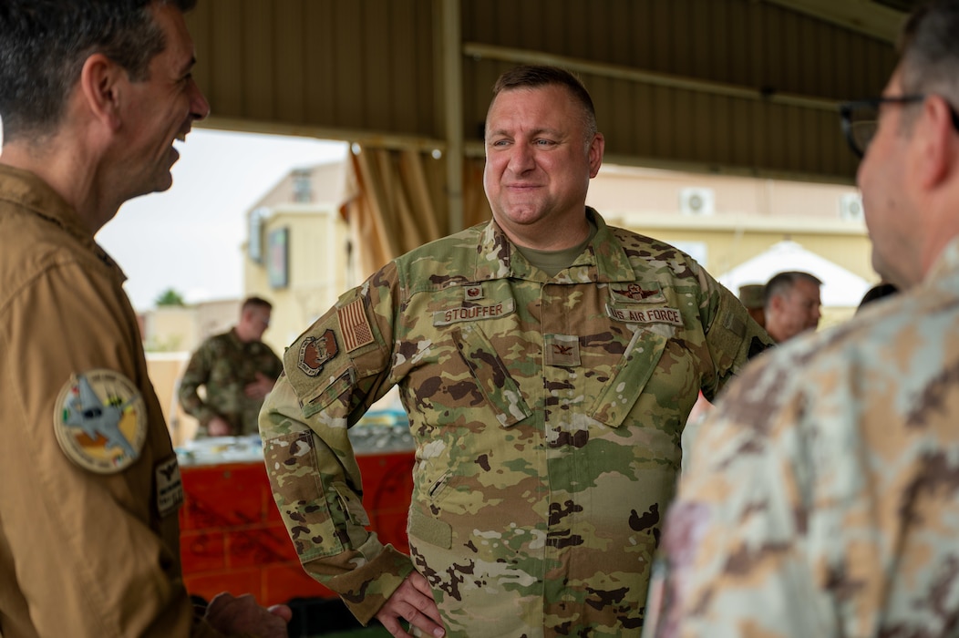 Col. Stouffer stands mid-frame as he listens attentively to a three-way conversation with Italian Air Force partners on either side of him