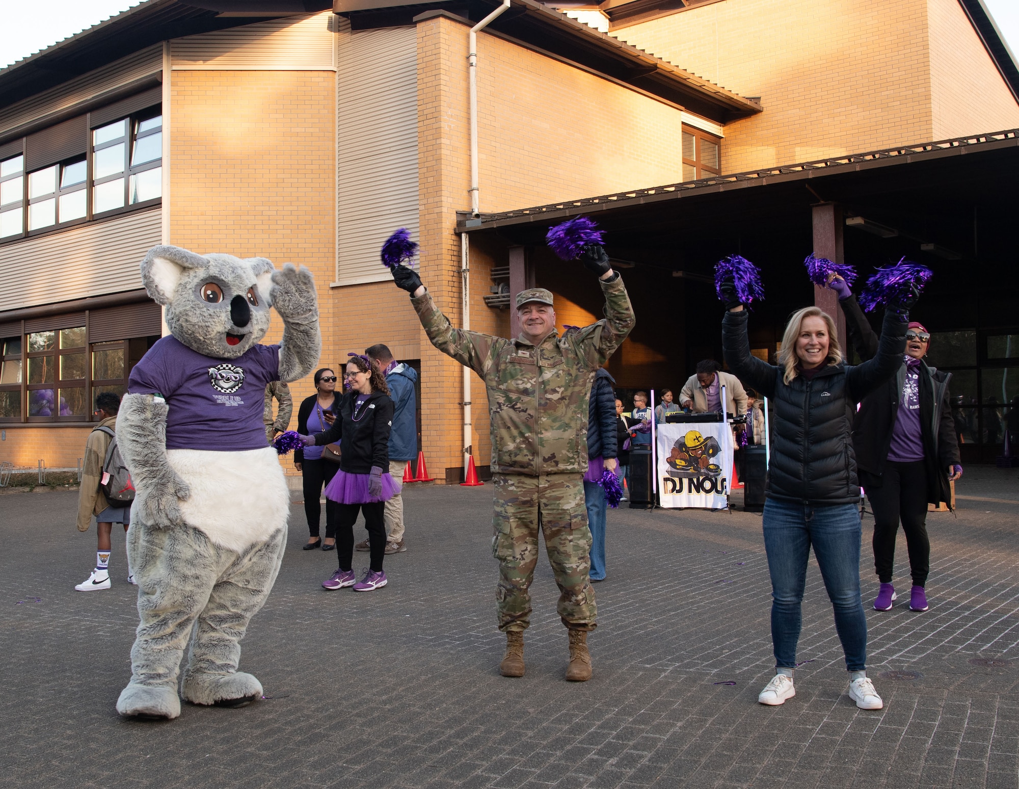 U.S. Air Force Col. James Cunningham, 86th Mission Support Group commander, his wife, Kim, and Kelly the Koala, Ramstein Elementary School’s mascot, wave to buses filled with children as they arrive at school on Ramstein Air Base, Germany, April 9, 2025.