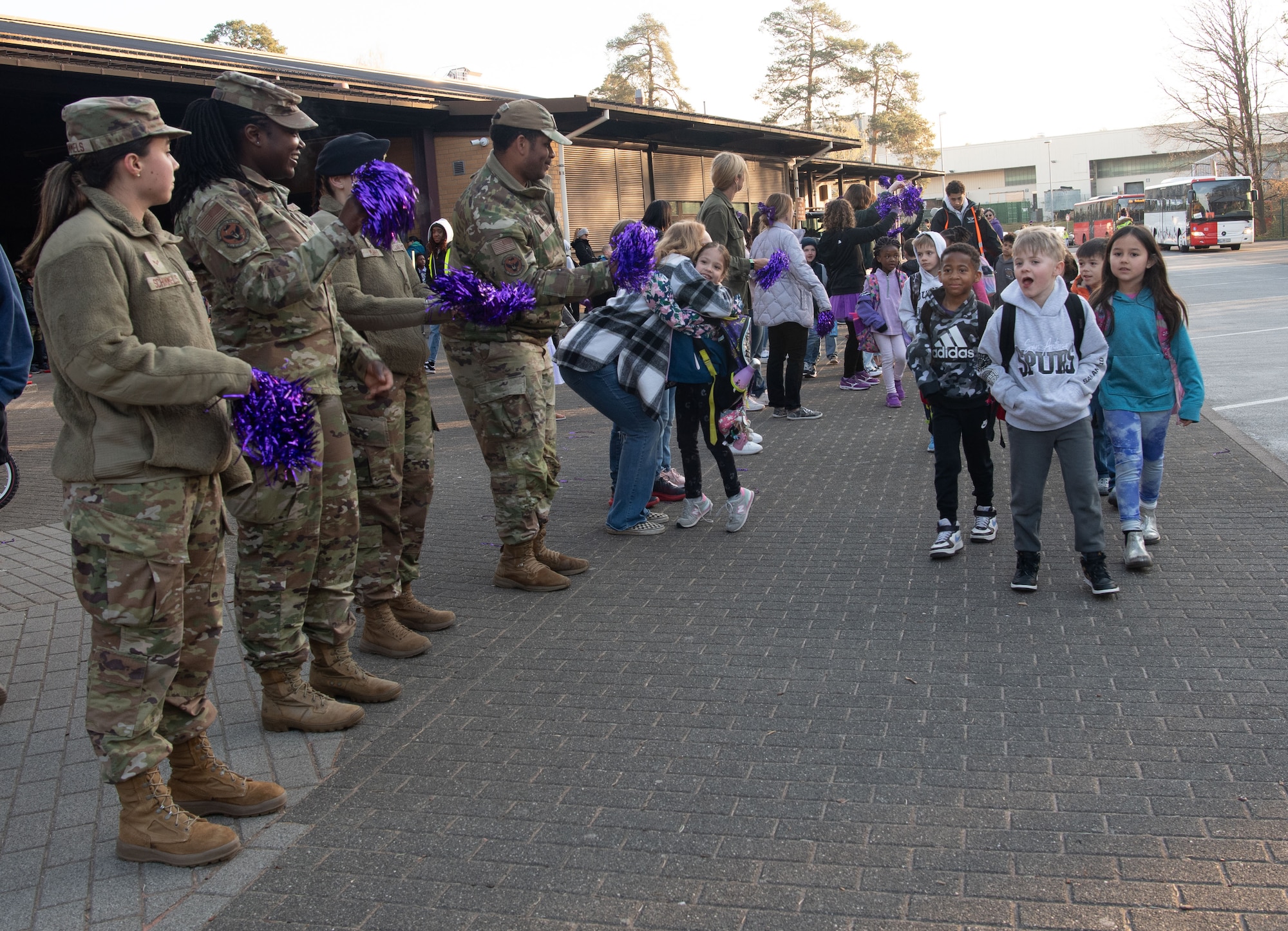 U.S. military members cheer on students arriving at Ramstein Elementary School during a Purple Up! Day event at Ramstein Air Base, Germany, April 9, 2025.