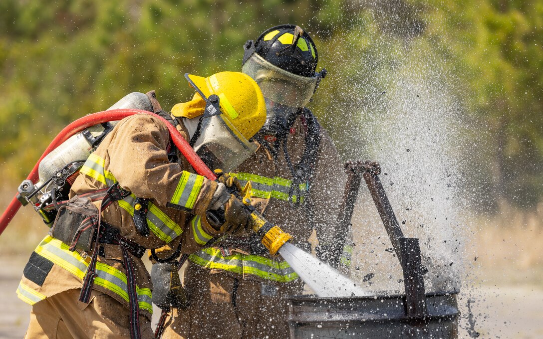 U.S. Marine Corps Lance Cpl. Alejandro Gonzalez, left, and Cpl. Gabriel Soto, both from California and aircraft rescue firefighters with Marine Wing Support Squadron (MWSS) 271, put out a fire during Base Recovery After Attack Training at Marine Corps Outlying Landing Field Atlantic, North Carolina, April 2, 2025. MWSS-271 conducted a squadron field exercise to improve the squadron's proficiency in providing aviation ground support to 2nd Marine Aircraft Wing. (U.S. Marine Corps photo by Cpl. David Ornelas Baeza)