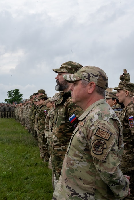 U.S. Air Force Lt. Col. Robert Ochsner, chemical, biological, radiological and nuclear enhanced response force package commander, 140th Medical Group, leads the integrated formation of the Colorado National Guard and State Partnership Program partner, the Republic of Slovenia, during the opening ceremony of the Vigorous Warrior and Clean Care 2024 medical exercises, May 3, 2024 at the at Bakonykúti Training Area, Hungary.