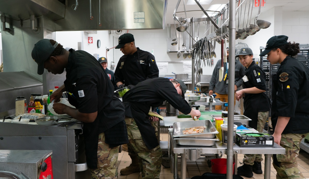 U.S. Air Force Airmen from the 354th Force Support Squadron and U.S. Army Soldiers from the 1st Infantry Brigade Combat Team, 11th Airborne Division prepare meals during the cooking competition at the Wolves Den Warrior Restaurant on Fort Wainwright, Alaska, March 27, 2025.
