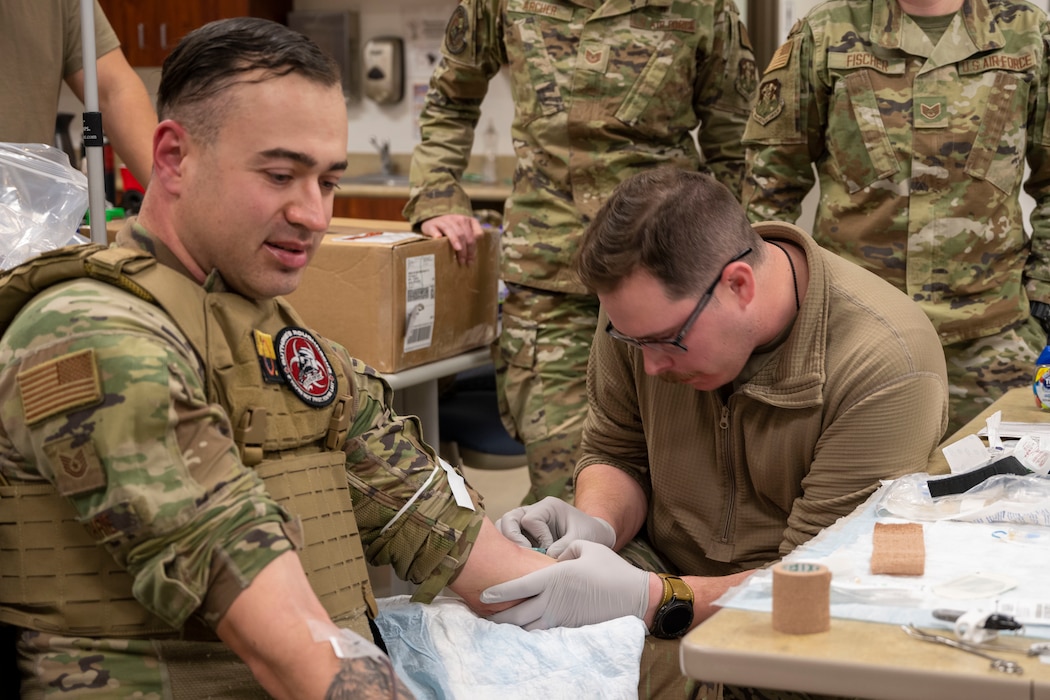 U.S. Air Force Staff Sgt. Brett McKinney (right), an aerospace medical technician with 140th Medical Group, prepares an IV for U.S. Air Force Tech. Sgt. Charles Guthrie during Tactical Combat Casualty Care training at Buckley Space Force Base, Jan. 28, 2025.