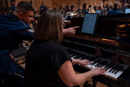 Tech. Sgt. Donmezer scrolls the sheet music displayed on an electronic tablet as the guest pianist plays.