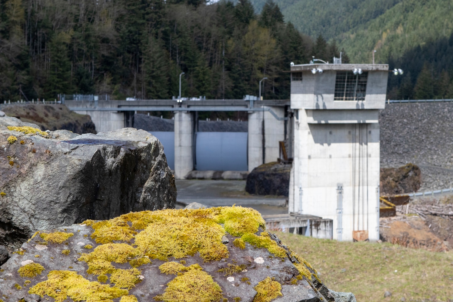Photo of Howard A. Hanson Dam, a U.S. Army Corps of Engineers dam, located near the headwaters of the Green River in King County. The dam is an earth and rockfill structure with inclined core drain and filters. Outlet works on the left bank consist of an approach channel, an intake structure providing upstream control, a 19-foot diameter horseshoe concrete-lined tunnel, a stilling basin, and an auxiliary 48-inch diameter bypass pipe.