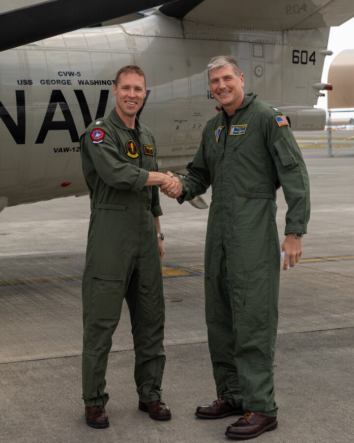 U.S. Navy Cmdr. Daniel Yates, left, the oncoming commanding officer of Airborne Command and Control Squadron (VAW) 125, and an Illinoi native, and Capt. Brian Kesselring, the commander of Carrier Air Wing (CVW) 5, and a North Dakota native, shake hands aircraft during a change of command ceremony at Marine Corps Air Station Iwakuni, April 3, 2025. During the change of command ceremony, Cmdr. Kai Siegele was relieved as commanding officer of VAW-125 by Cmdr. Daniel Yates. (U.S. Marine Corps photo by Cpl. Colin Thibault)