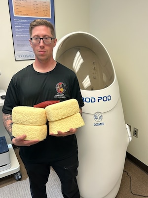 SFC Joseph Swartz is holding pounds of fat showing how much weight he has lost.