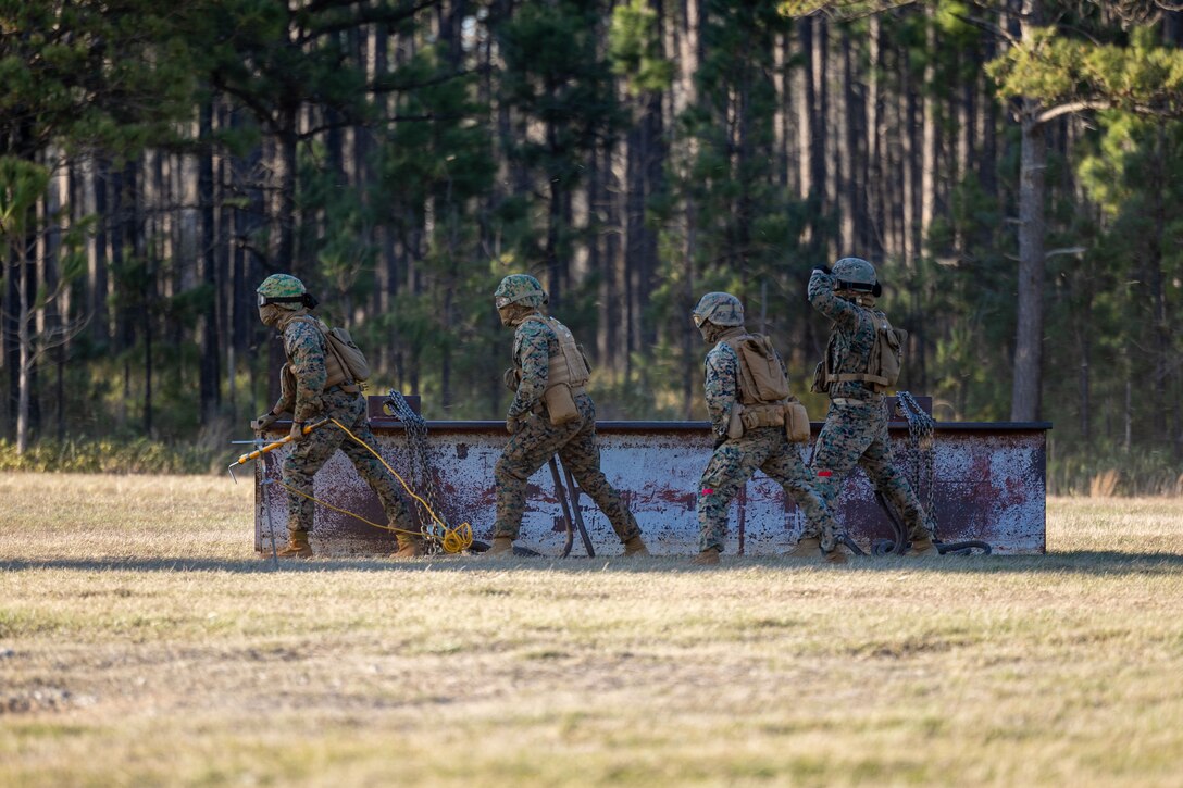 U.S. Marines with Combat Logistics Battalion 25, 4th Marine Logistics Group, withstand high winds from a CH-53E Super Stallion assigned to Marine Heavy Helicopter Training Squadron 302 (HMHT-302), Marine Aircraft Group 29 (MAG-29), 2nd Marine Aircraft Wing (2nd MAW) ,during a helicopter support team training at Camp Lejeune, North Carolina, Mar. 27, 2025. Landing support specialists and pilots conducted HST to familiarize themselves with insertions and extractions of heavy loads to increase their proficiency in combat scenarios. (U.S. Marine Corps photo by Cpl. Salvador Flores Perez)