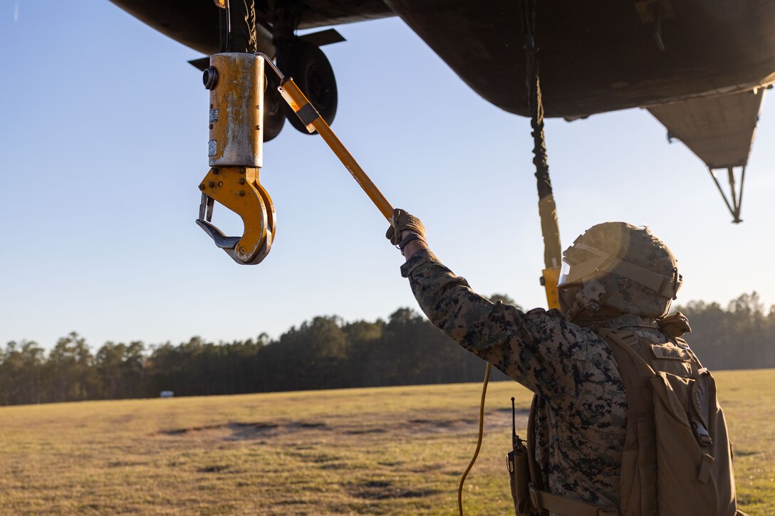 U.S. Marine Corps Cpl. Noah J. McGhee, landing support team leader with Combat Logistics Battalion 25, 4th Marine Logistics Group, discharges a cargo cable with a grounding hook from a CH-53E Super Stallion assigned to Marine Heavy Helicopter Training Squadron 302 (HMHT-302), Marine Aircraft Group 29 (MAG-29), 2nd Marine Aircraft Wing (2nd MAW), during Helicopter Support Team training at Camp Lejeune, North Carolina, Mar. 27, 2025. Landing support specialists and pilots conducted HST to familiarize themselves with insertions and extractions of heavy loads to increase their proficiency in combat scenarios. (U.S. Marine Corps photo by Cpl. Salvador Flores Perez)
