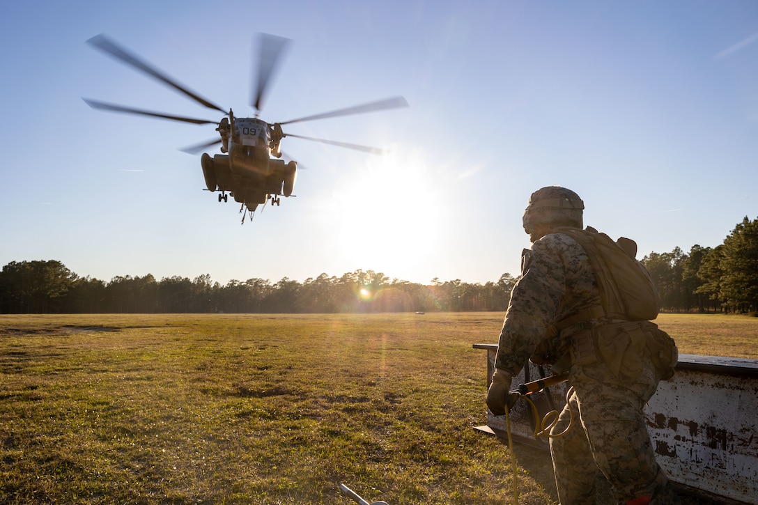 U.S. Marine Corps Cpl. Noah J. McGhee, landing support team leader with Combat Logistics Battalion 25, 4th Marine Logistics Group, awaits an oncoming CH-53E Super Stallion assigned to Marine Heavy Helicopter Training Squadron 302 (HMHT-302), Marine Aircraft Group 29 (MAG-29), 2nd Marine Aircraft Wing (2nd MAW), during Helicopter Support Team training at Camp Lejeune, North Carolina, Mar. 27, 2025. Landing support specialists and pilots conducted HST to familiarize themselves with insertions and extractions of heavy loads to increase their proficiency in combat scenarios. (U.S. Marine Corps photo by Cpl. Salvador Flores Perez)