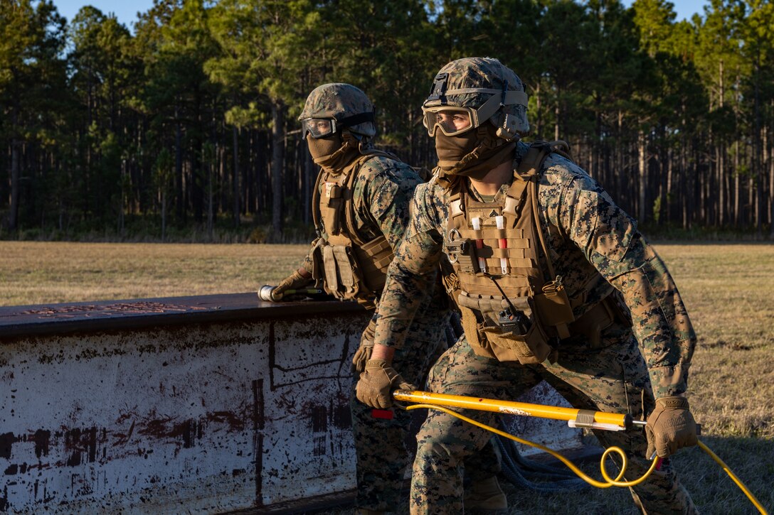 U.S. Marine Corps Cpl. Noah J. McGhee, right, landing support team leader, and Lance Cpl. Refugio Estrella, landing support specialist, both with Combat Logistics Battalion 25, 4th Marine Logistics Group, withstand high winds from an incoming CH-53E Super Stallion assigned to Marine Heavy Helicopter Training Squadron 302 (HMHT-302), Marine Aircraft Group 29 (MAG-29), 2nd Marine Aircraft Wing (2nd MAW), during a helicopter support team training at Camp Lejeune, North Carolina, Mar. 27, 2025. Landing support specialists and pilots conducted HST to familiarize themselves with insertions and extractions of heavy loads to increase their proficiency in combat scenarios. (U.S. Marine Corps photo by Cpl. Salvador Flores Perez)