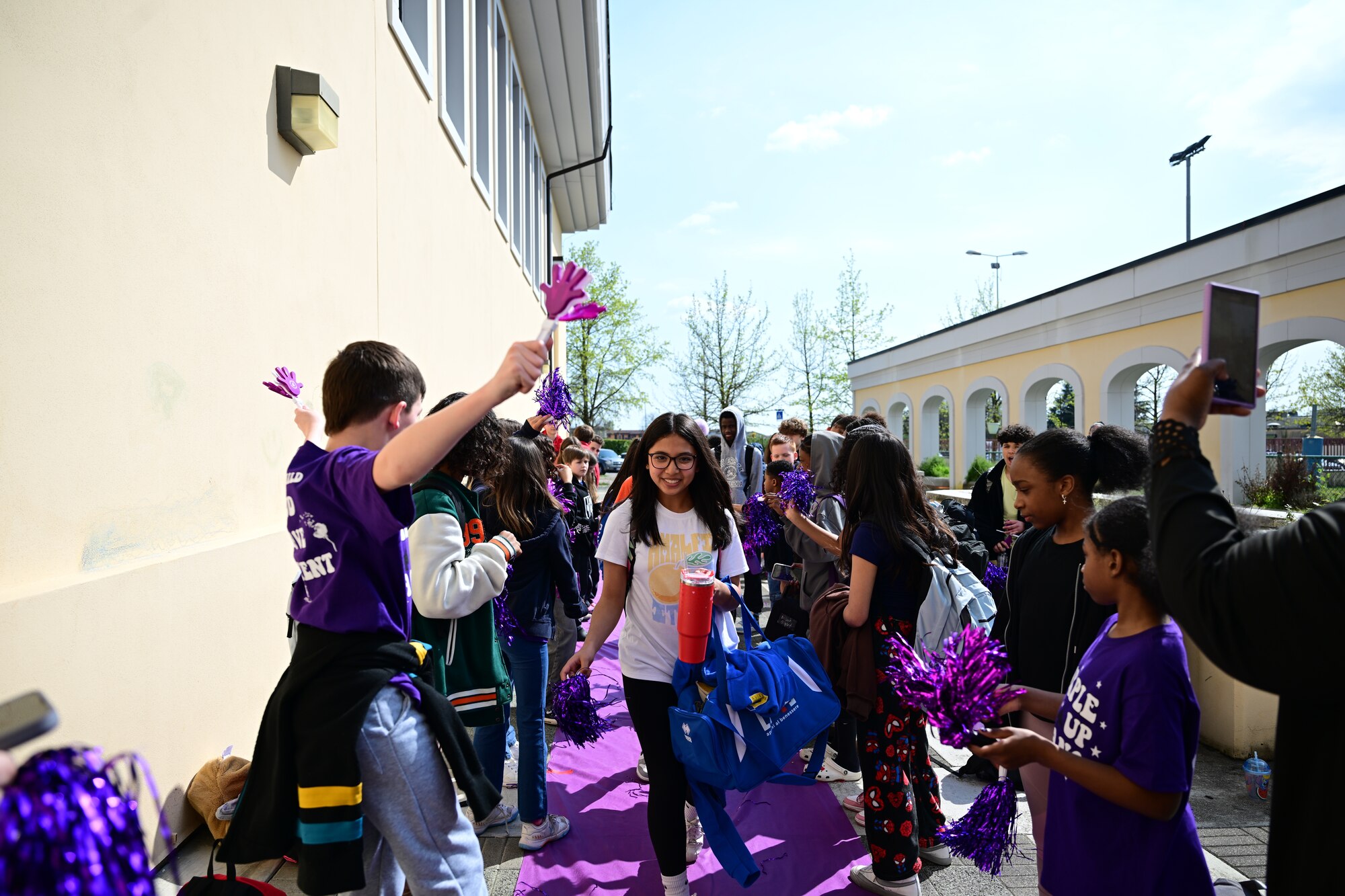 Students walk on a purple carpet and cheer on their peers.