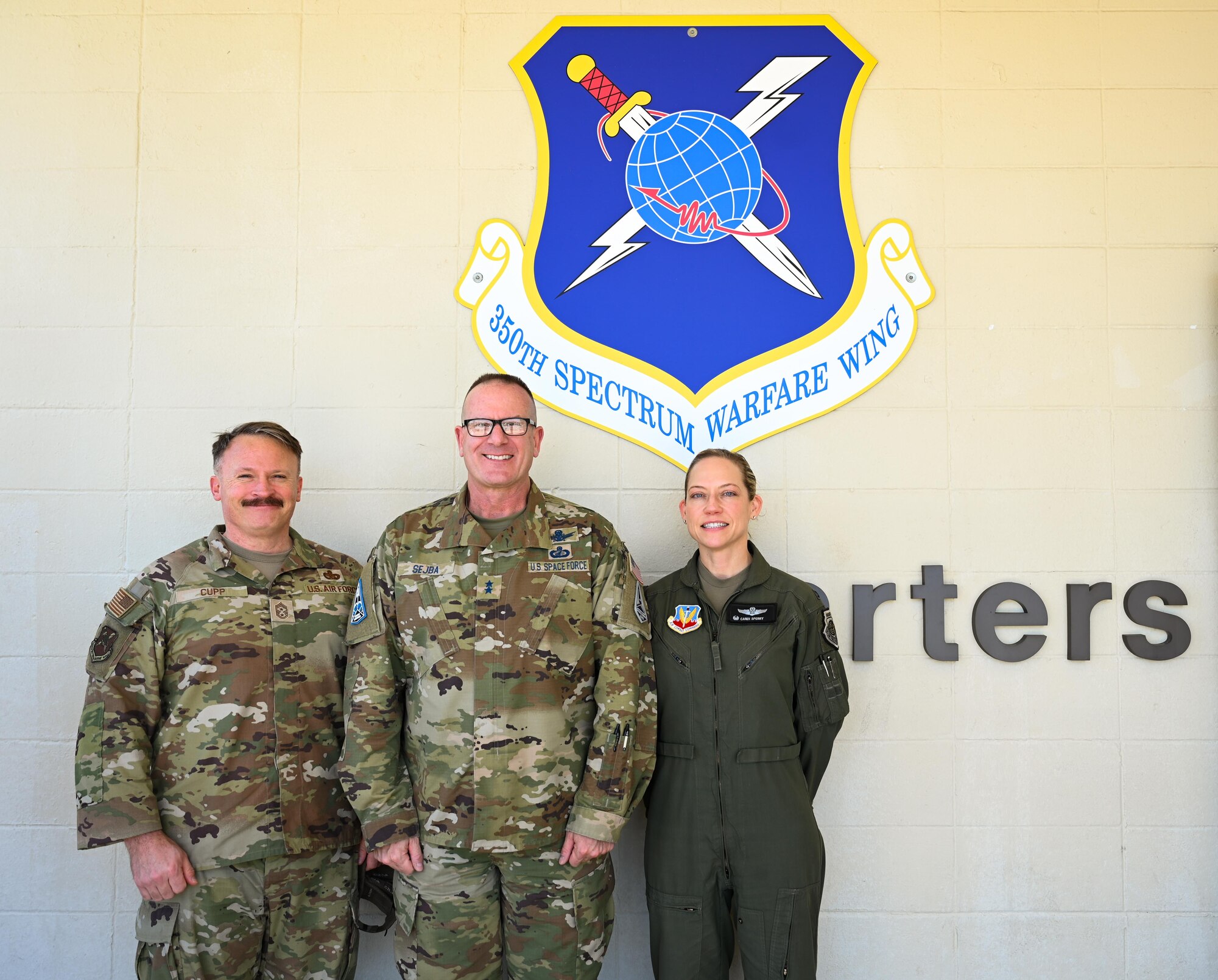 U.S. Air Force Chief Master Sgt. Will Cupp, 350th Spectrum Warfare Wing command chief, left, U.S. Space Force Maj. Gen. Timothy Sejba, Space Training and Readiness Command commander, middle, and U.S. Air Force Col. Candice Sperry, 350th Spectrum Warfare Group commander, right, post for a photo at the start of his visit to the 350th Spectrum Warfare Wing at Eglin Air Force Base, Florida, April 8, 2025. The visit offered an opportunity to discuss the missions of the 350 SWW and STARCOM and shared mission equities between both units. (U.S. Air Force photo by Capt. Benjamin Aronson)