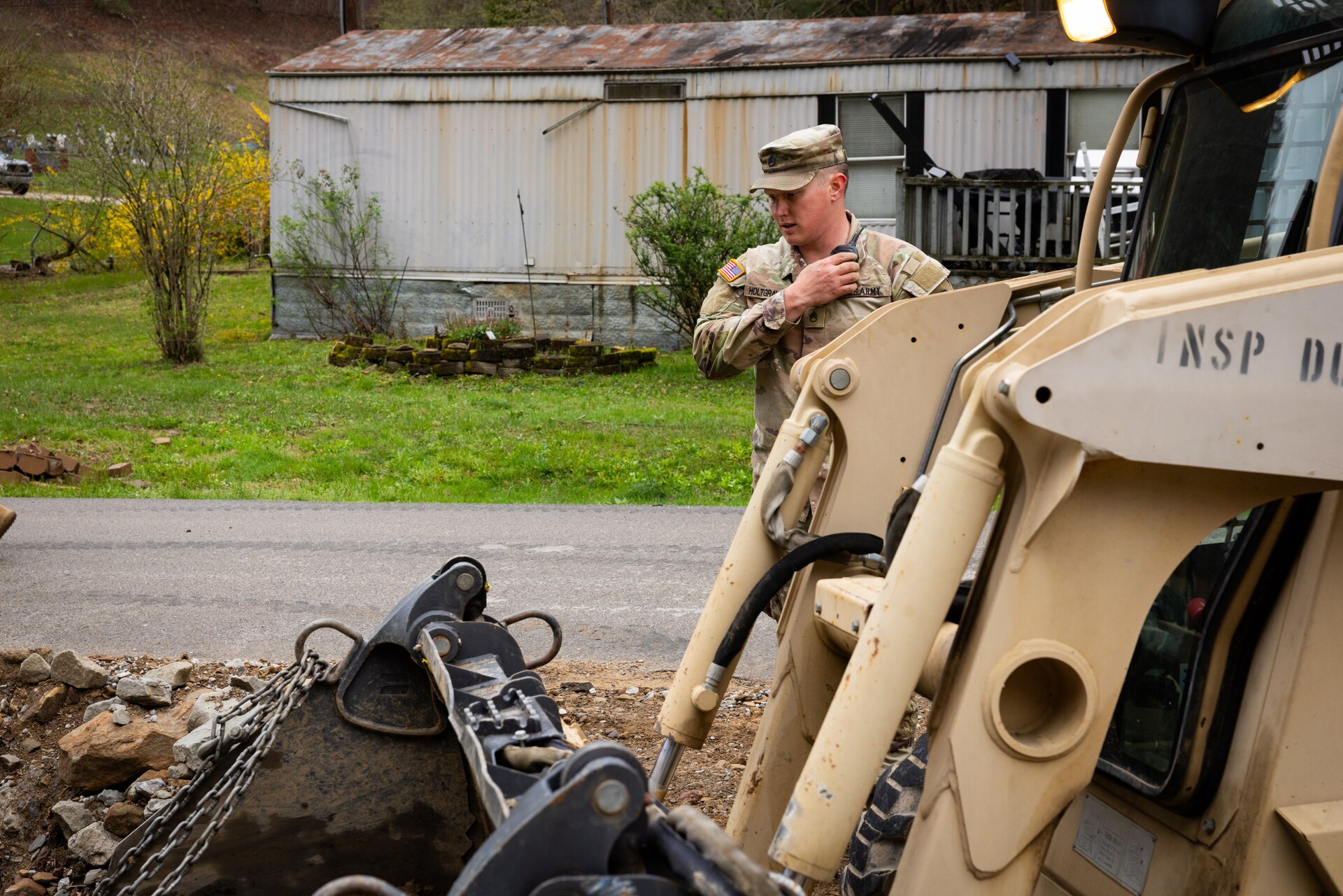 U.S. Army Staff Sgt. Micheal Holtgraver uses his radio to talk with his skid steer operator to repair critically damaged county roads in Hindman, Ky. on April 1, 2025. Holtgraver and members of Detachment 1, 149th Vertical Construction Company, 149th Maneuver Enhancement Brigade have been working for over a month to help counties repair critical roads since flooding in February. (U.S. Army National Guard photo by Andy Dickson)