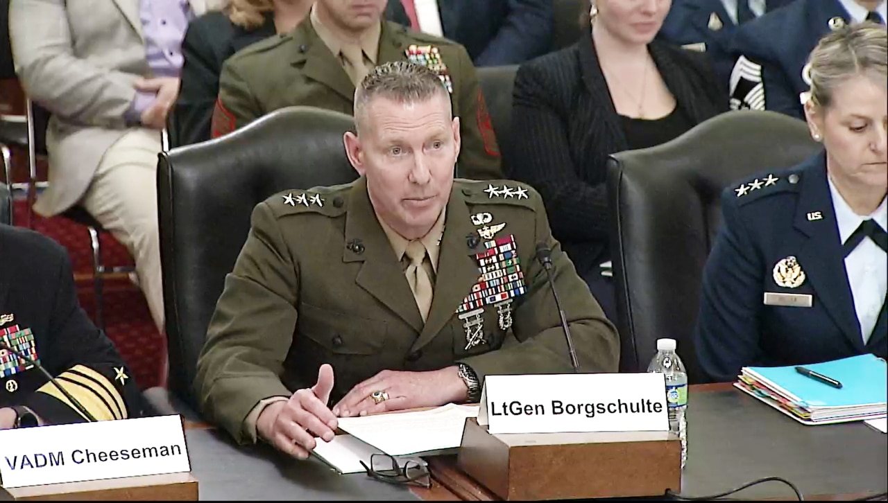 A man in a military uniform sits at a wooden table.