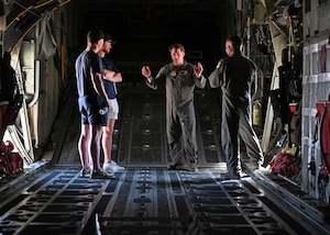 U.S. Air Force Staff Sgt. Ryan Murphy, 79th Rescue Squadron instructor loadmaster, center, briefs members of Tucson Roadrunners, a local minor league hockey team, about the capabilities of the HC-130J Combat King II aircraft at Davis-Monthan Air Force Base, Arizona, April 8, 2025. The 355th Wing supports civic member tours to facilitate open and honest communication with community members about the mission, vision and priorities of the wing. (U.S. Air Force photo by Staff Sgt. Abbey Rieves)