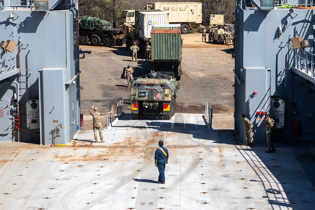 Army equipment is moved off of a transport vessel.