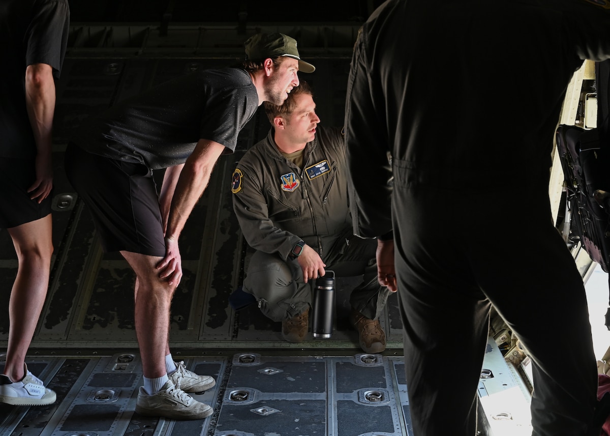 U.S. Air Force Staff Sgt. Ryan Murphy, 79th Rescue Squadron instructor loadmaster, center, briefs members of Tucson Roadrunners, a local minor league hockey team, about the capabilities of the HC-130J Combat King II aircraft at Davis-Monthan Air Force Base, Arizona, April 8, 2025. The 355th Wing values a strong community partnership as a way to generate greater local support and understanding for the Wing’s initiatives and services. (U.S. Air Force photo by Staff Sgt. Abbey Rieves)