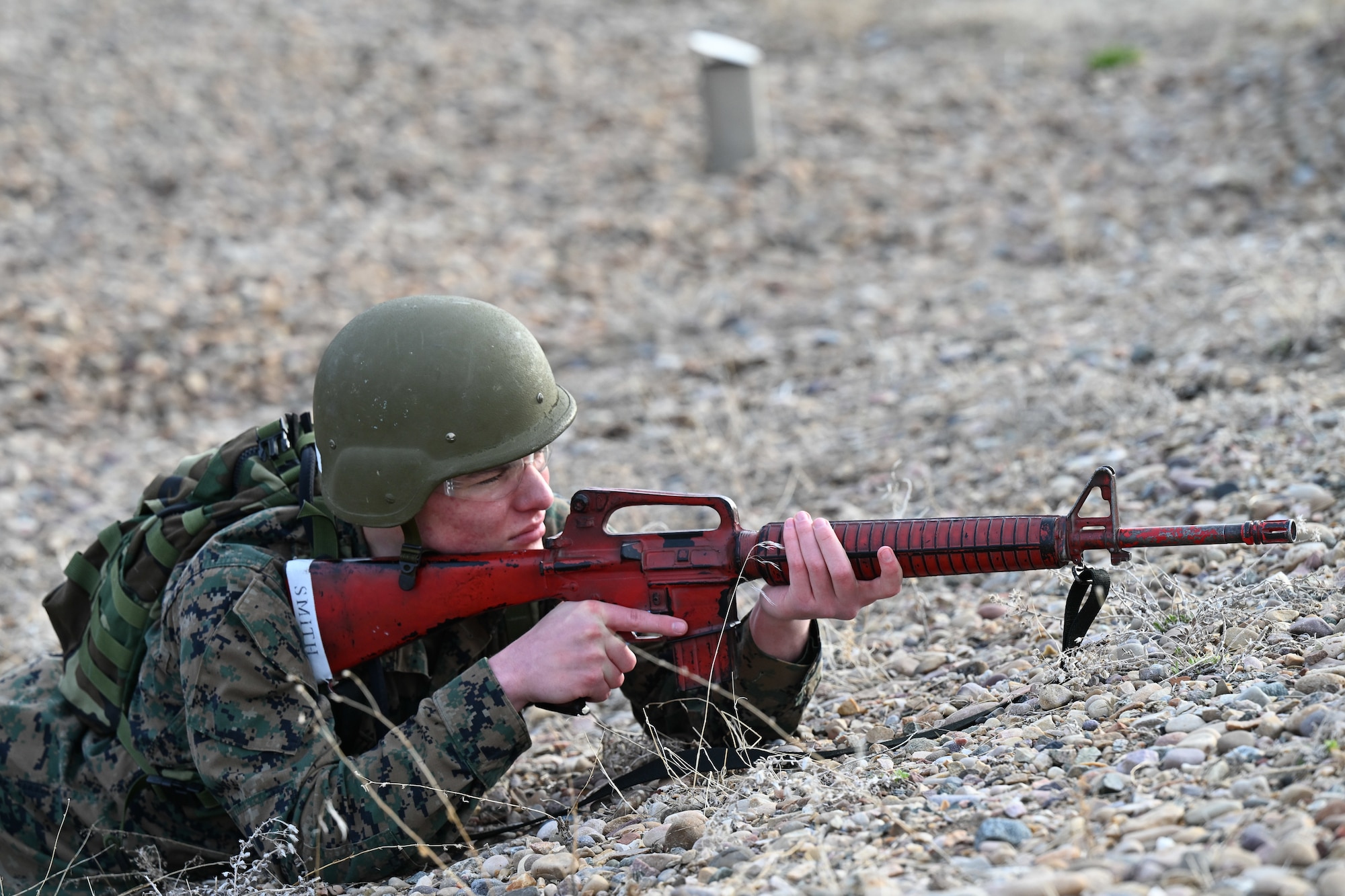 An ROTC student lays on ground with fake weapon to take aim