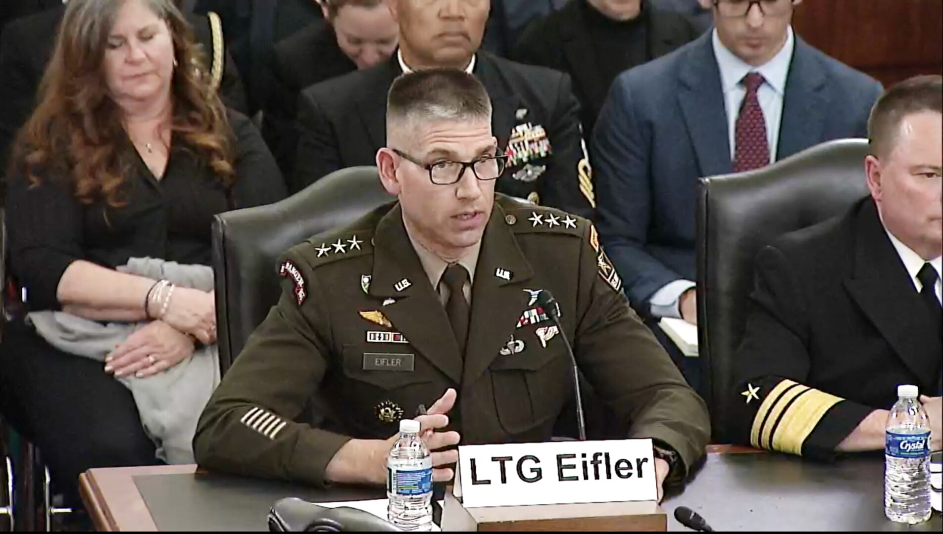 A man in a military uniform sits at a wooden table.