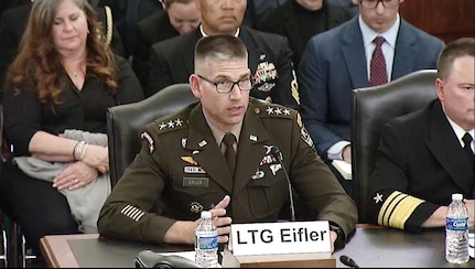 A man in a military uniform sits at a wooden table.