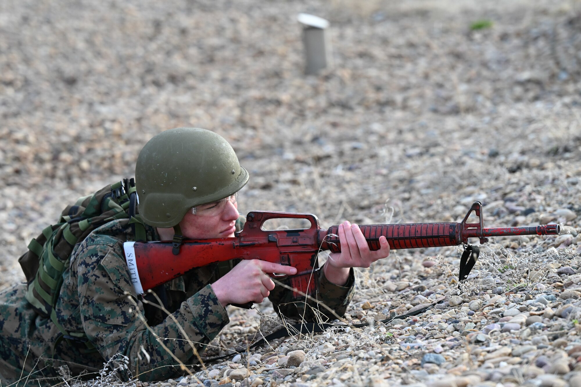 An ROTC student lays on ground with fake weapon to take aim