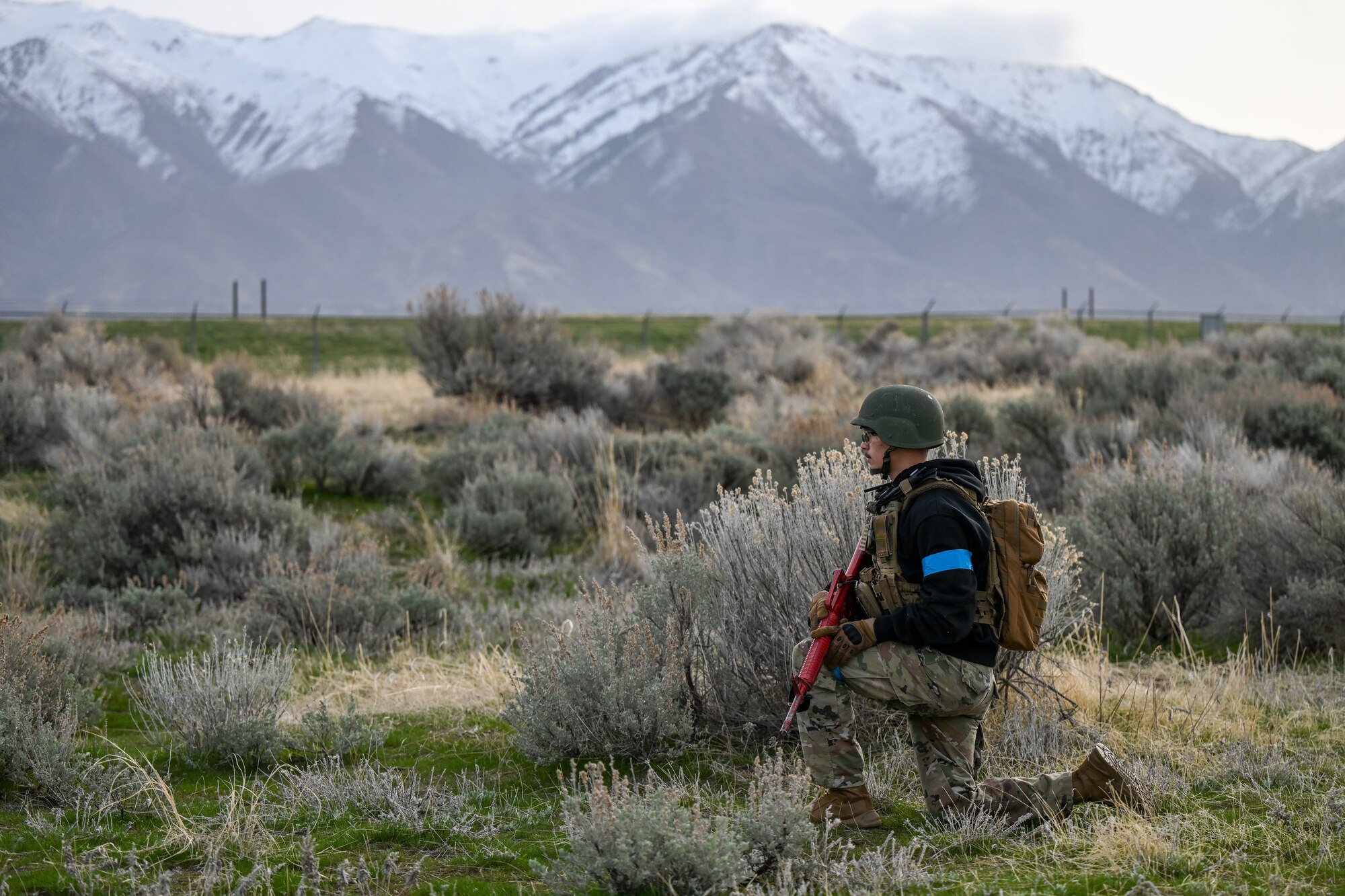 ROTC student with weapon stands guard kneeling with mountain background