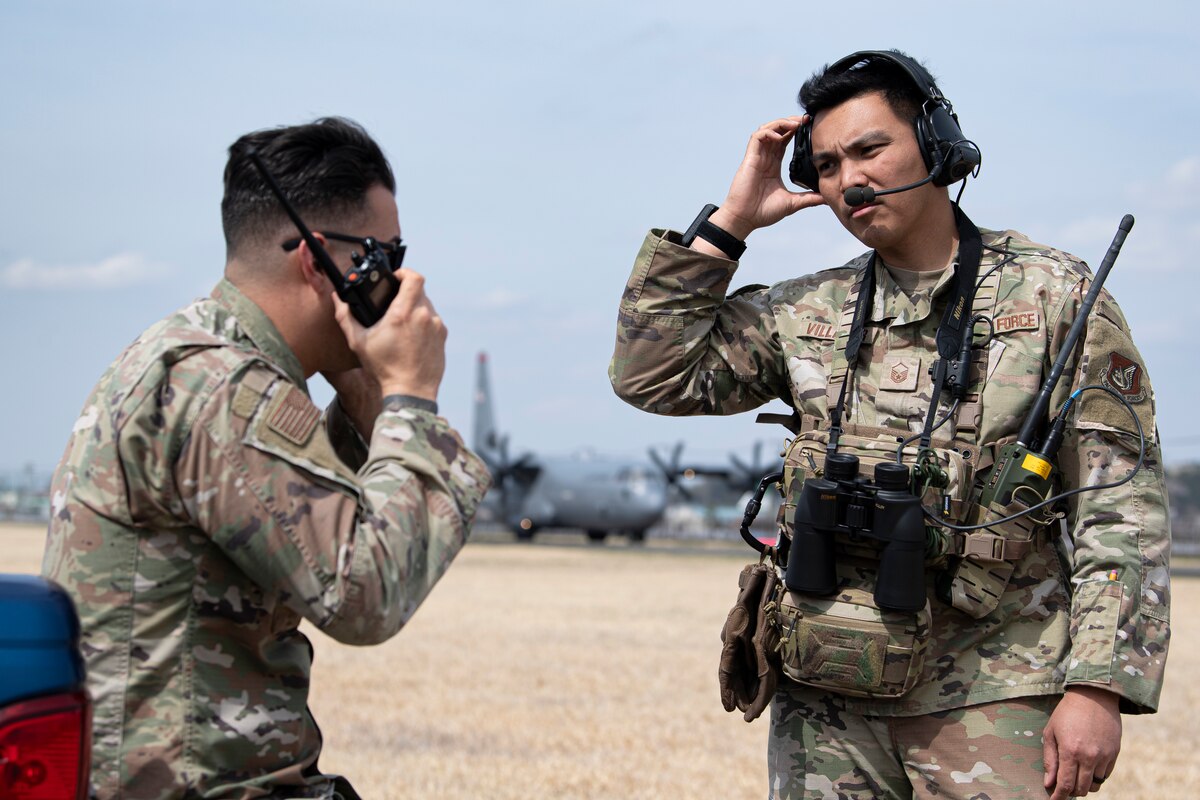 Two Airmen coordinate runway operations with the air traffic control tower.