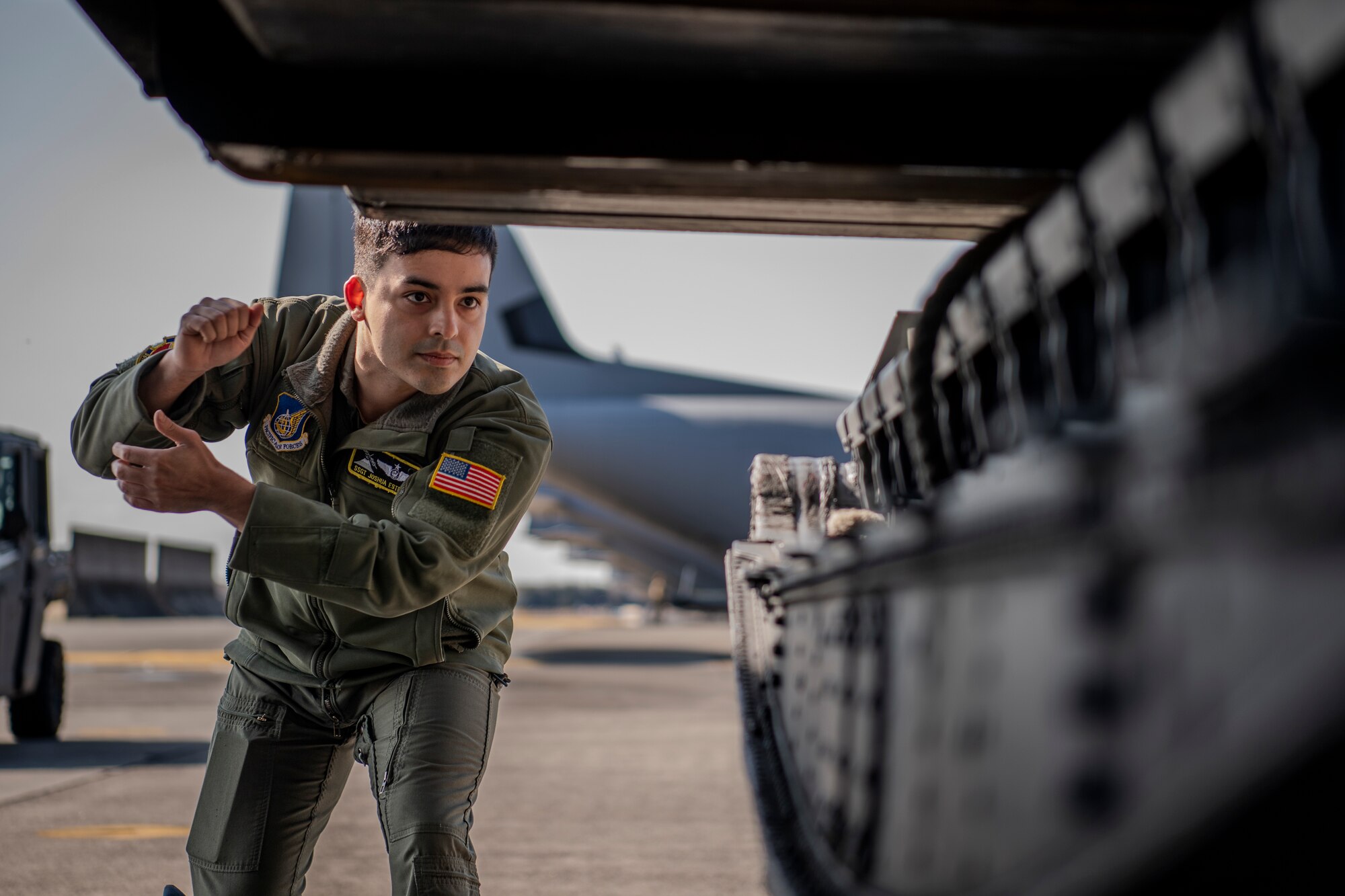 Airmen guides cargo onto aircraft