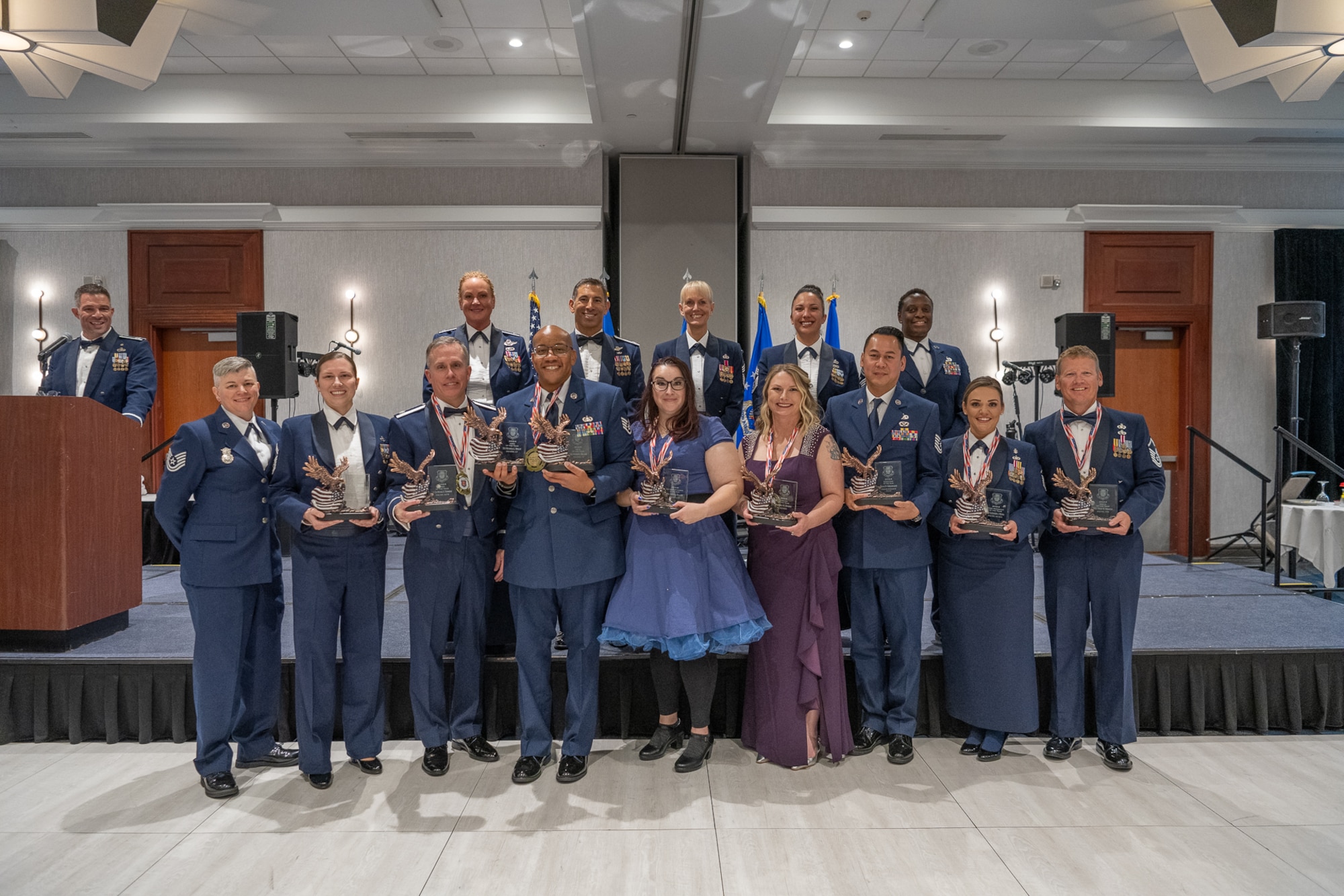 A row of people standing on a stage holding statuettes.