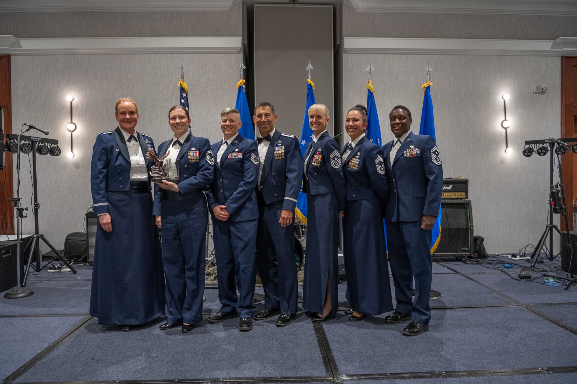 A row of servicemembers stand on stage.