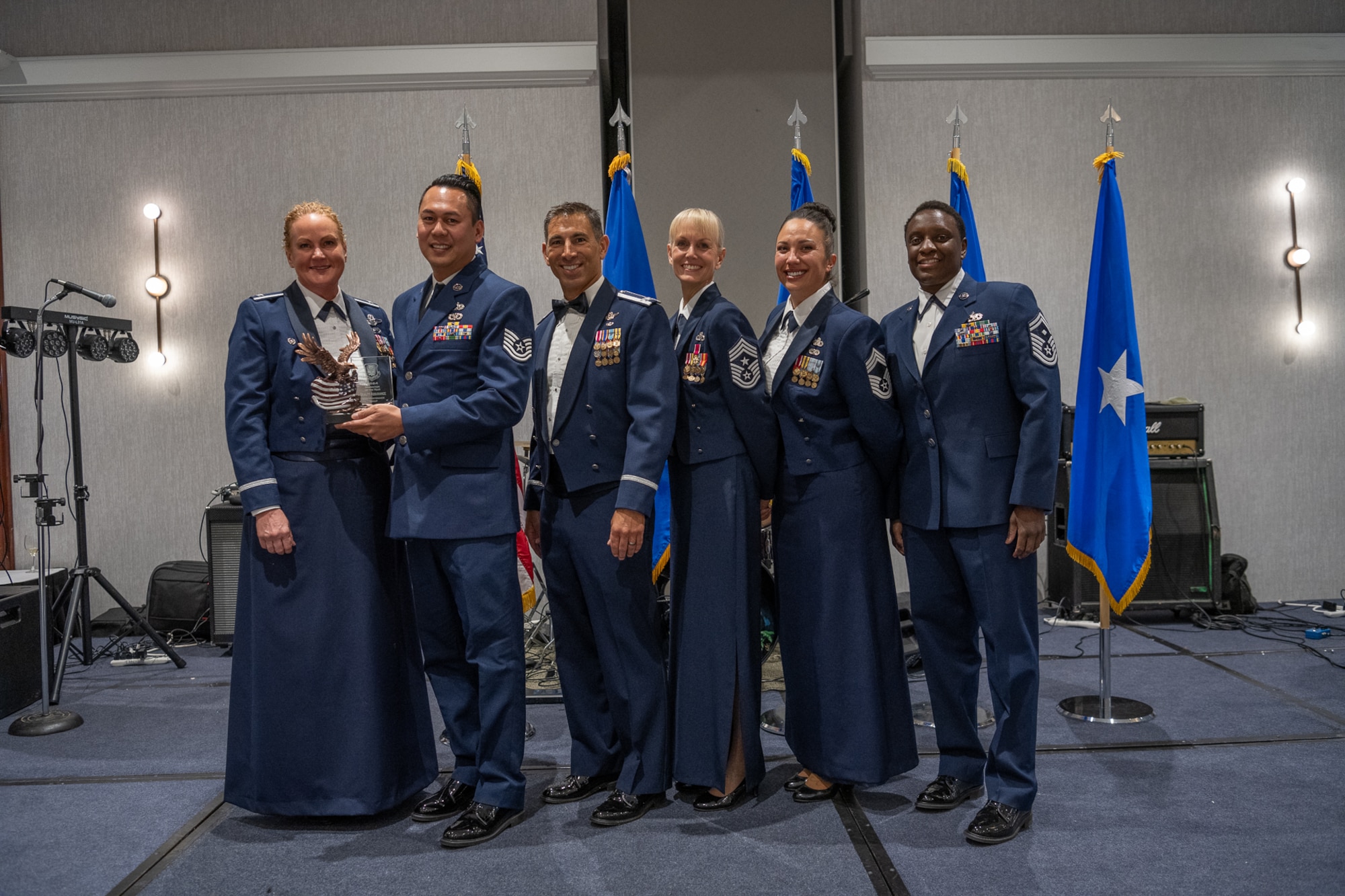 A row of servicemembers stand on stage.